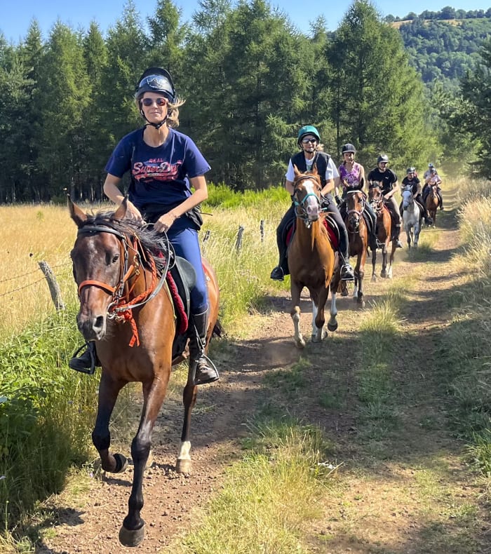 Randonnée équestre en vallée de la Jordanne au coucher du soleil avec deux cavaliers à cheval dans l'eau