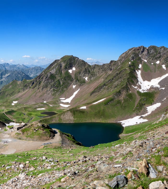 Vallée pyrénéenne de Campan avec lac alpin, pentes vertes et Pic du Midi de Bigorre au loin pour randonnée multi-activités