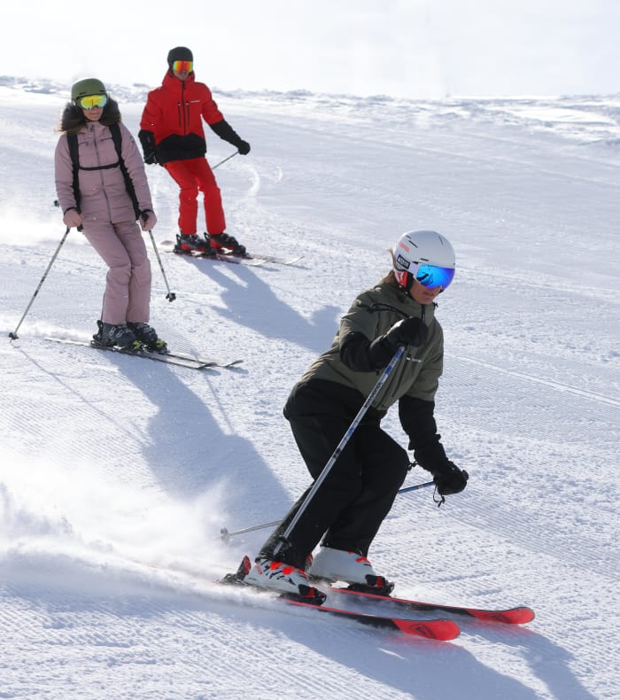 Groupe de skieurs descendant une piste enneigée à Val Thorens sous un ciel bleu dégagé avec moniteur encadrant les participants du Ski Pack Mi-temps