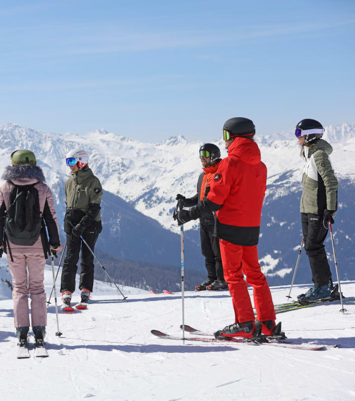 Deux skieurs en descente sur les pistes enneigées de Val Thorens par beau temps avec pics montagneux en arrière-plan