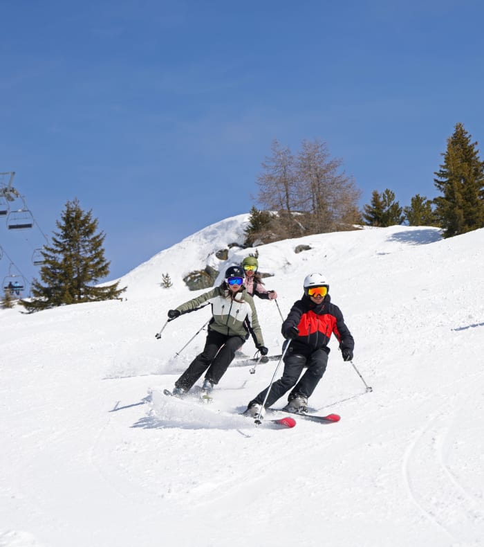 Trois skieurs dégringolant une piste enneigée aux Orres par beau temps ensoleillé