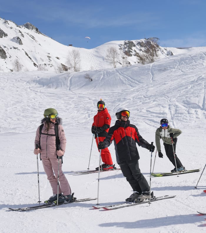 Skieur en combinaison jaune descendant une piste enneigée des Arcs sous le soleil avec montagnes en arrière-plan