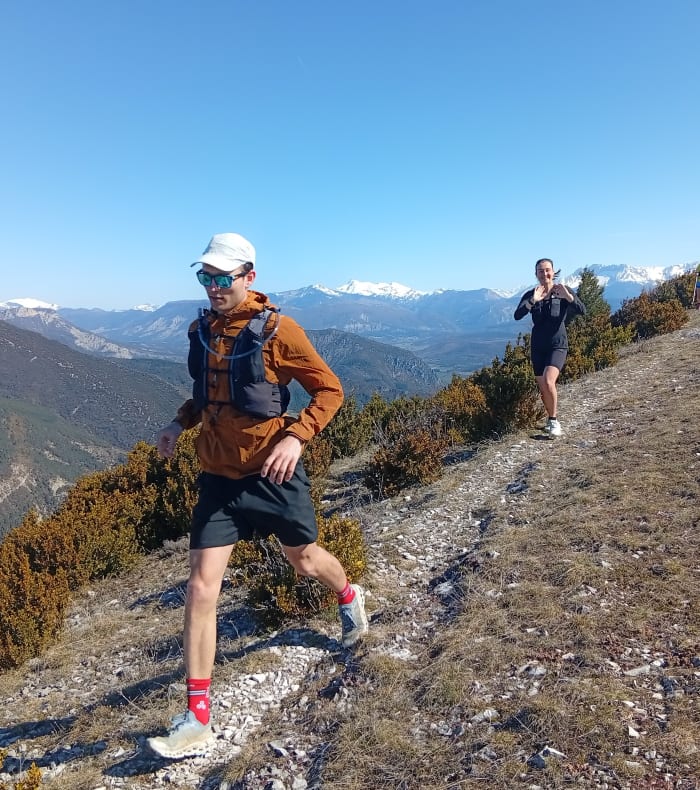 Trailers courant sur un sentier montagneux des Baronnies provençales avec vue panoramique sur les vallées et sommets enneigés
