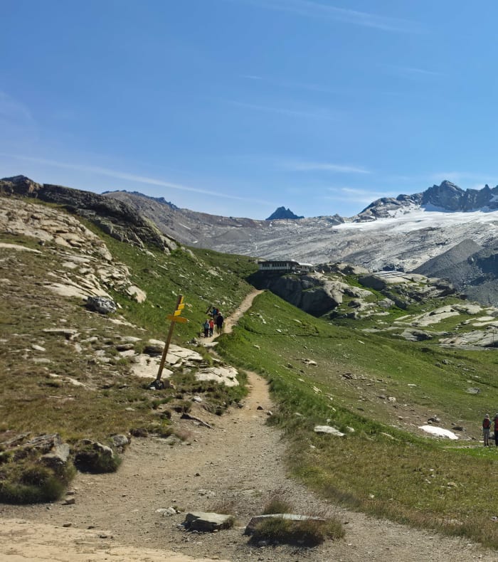Randonneurs sur sentier de montagne en Haute Maurienne avec glaciers et sommets rocheux en arrière-plan