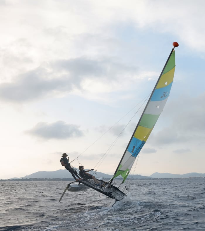 Windsurfeur en gilet de sauvetage jaune manœuvrant une voile jaune et noire sur la Méditerranée en Camargue