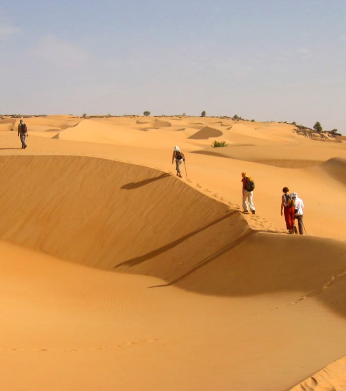 Trekking en groupe dans les dunes de l'Erg Amatlich avec randonneurs traversant les sables du désert