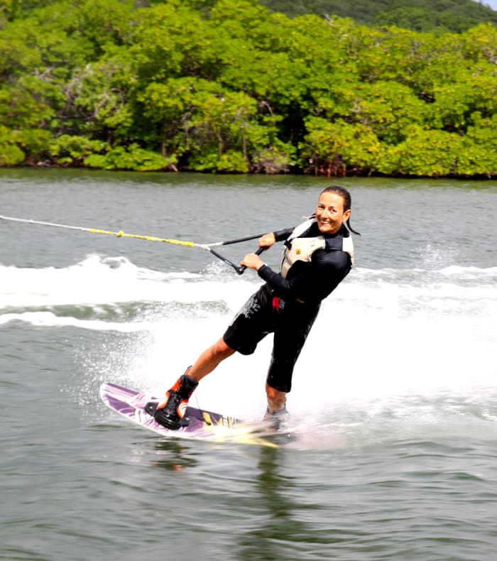 Homme pratiquant le wakeboard sur une plage de Martinique avec végétation tropicale en arrière-plan