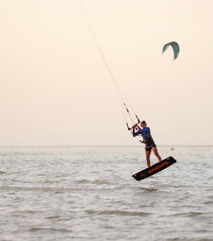 Moniteur et kitesurfeur en équipement de sécurité face à une voile bleue sur la plage de l'Espiguette en Camargue