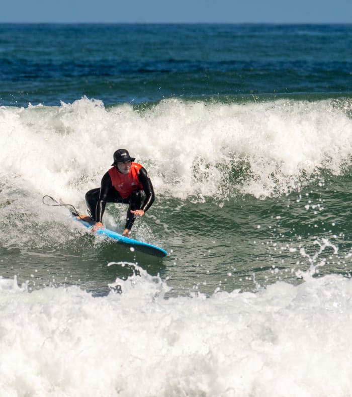 Surfeur en combinaison rouge chevauchant une vague bleue à la Torche en Bretagne