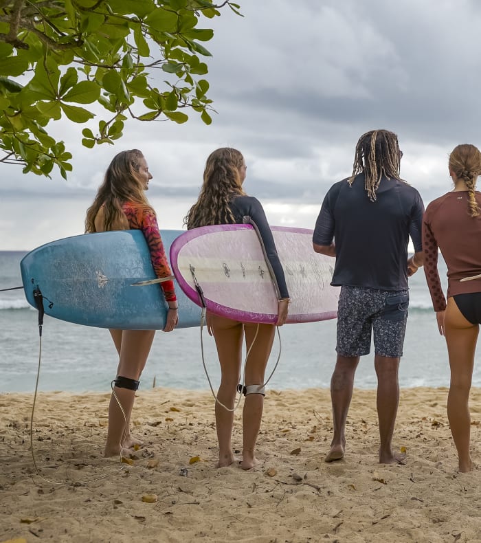 Groupe de jeunes surfeurs avec planches colorées sur la plage des Antilles face à l'océan