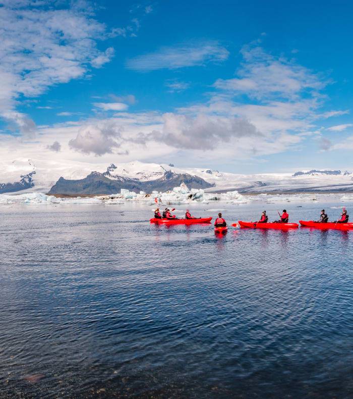 Kayak de mer au Spitzberg entre icebergs et glaciers avec participants en embarcations rouges et jaunes
