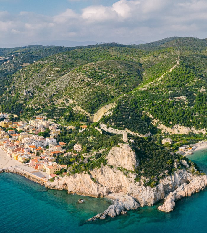 Village perché de Ligurie en bord de mer avec falaises calcaires, plage et montagnes boisées