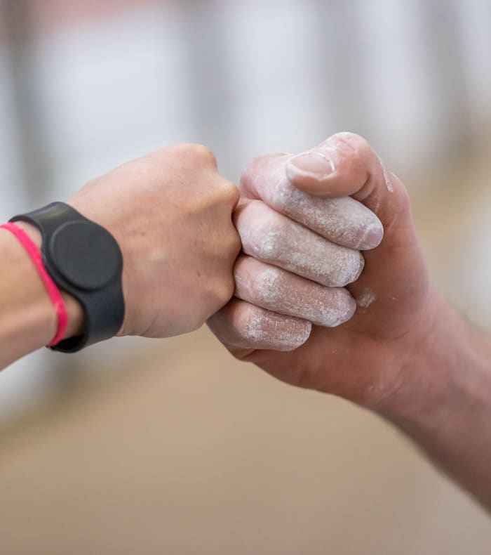 Deux personnes se donnent un coup de poing avec montre de sport et bracelet rose, symbole de motivation et d'engagement sportif