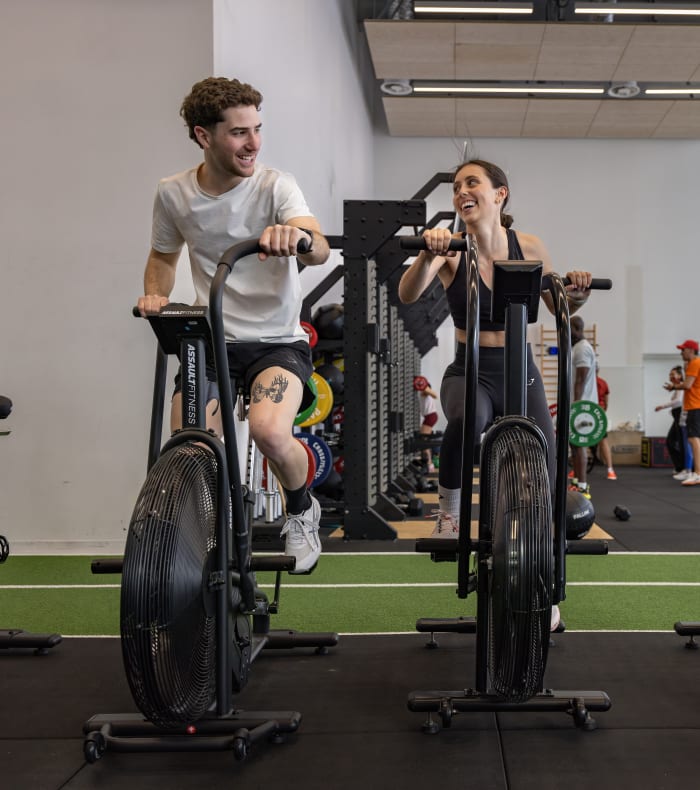 Homme et femme pratiquant le vélo en salle pour perdre du poids dans une salle de sport équipée