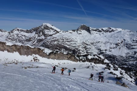 Un groupe de randonneurs en raquettes marche dans les Encantats