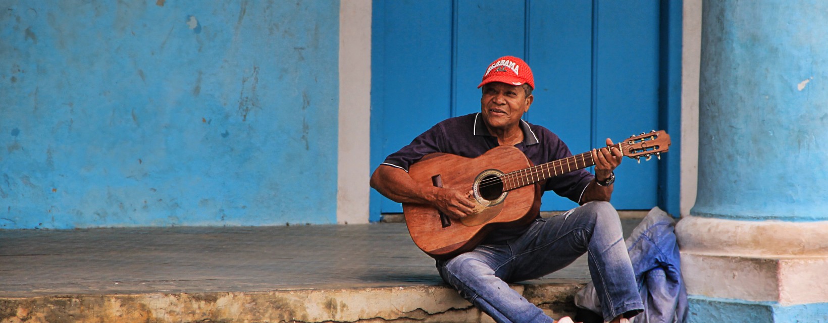 Un homme joue de la guitare assis sur le bord des escaliers à Cuba
