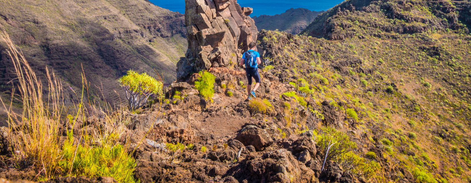 Un randonneur marche sur la crête d'une montagne face à l'océan