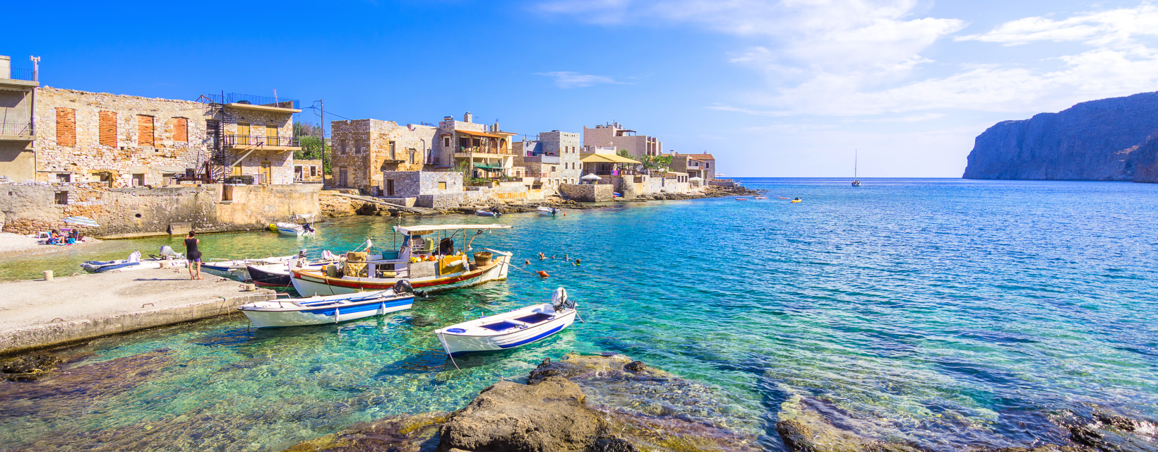 Un petit village au bord de mer avec son port de barques traditionnelles et une eau cristalline