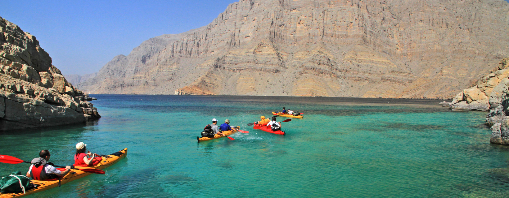 Des kayakistes sur une eau turquoises entourés par les montagnes d'Oman